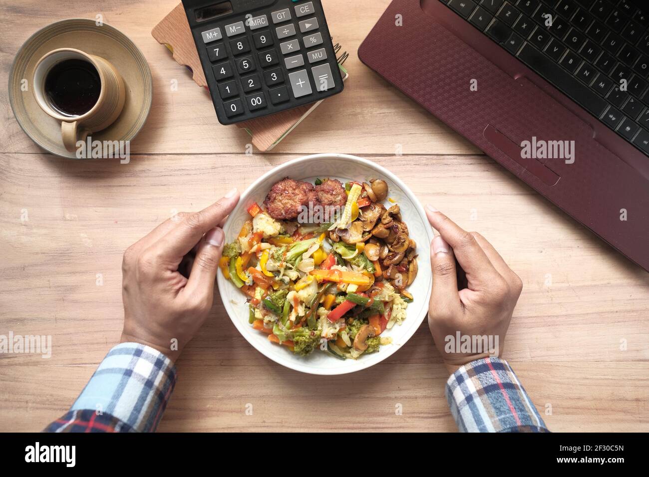 young man eating fresh salad while working on laptop  Stock Photo