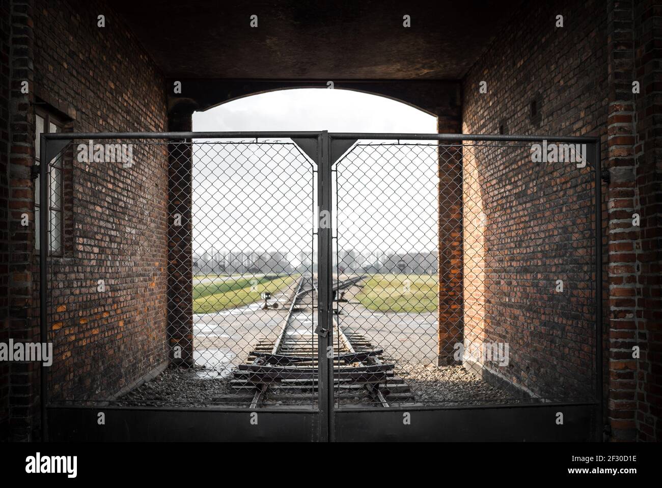 Auschwitz Birkenau II Concentration Extermination Camp Oswiecim Poland guard tower over gatehouse train entrance no people gate locked looking through Stock Photo