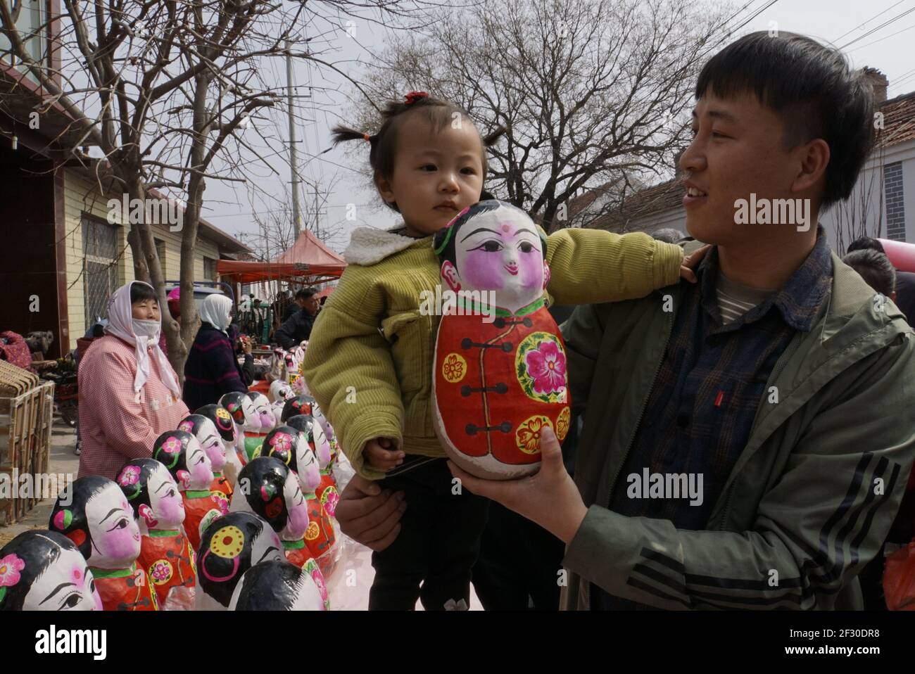 Huimin, China's Shandong Province. 14th Mar, 2021. A tourist buys a clay sculpture during a cultural festival in Zaohuli Town of Huimin County, east China's Shandong Province, March 14, 2021. Huimin County has a long history of clay sculpture creation, and local people celebrate the Longtaitou Day by making clay sculptures and performing yangge dance. The day of Longtaitou, which literally means 'dragon raises head', falls on the second day of the second lunar month. People celebrate the day with various activities. Credit: Fan Changguo/Xinhua/Alamy Live News Stock Photo