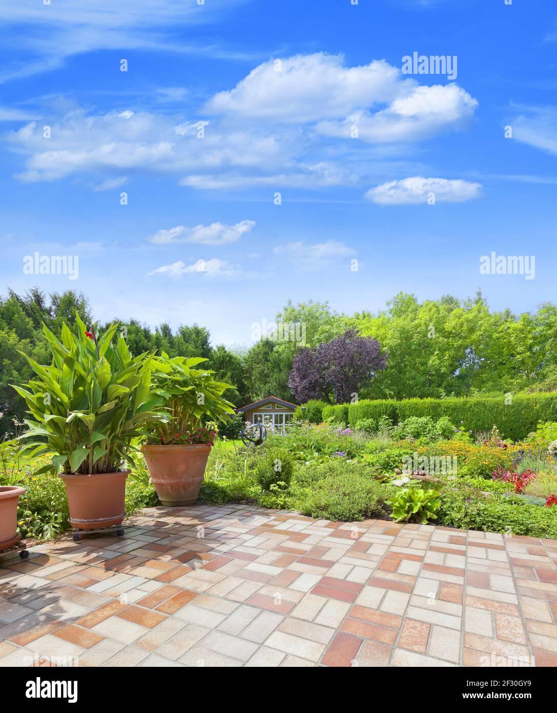 Beautiful, well-kept garden terrace with a colorful flowerbed and garden pond. Stock Photo