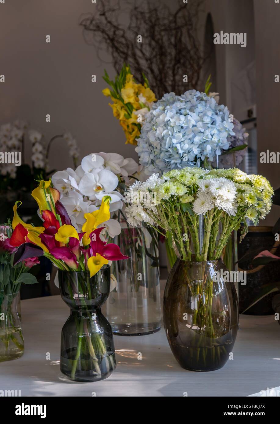 Beautiful bouquet of flowers in Assorted many different glass vases in flower shop. Home decor. Selective focus. Stock Photo