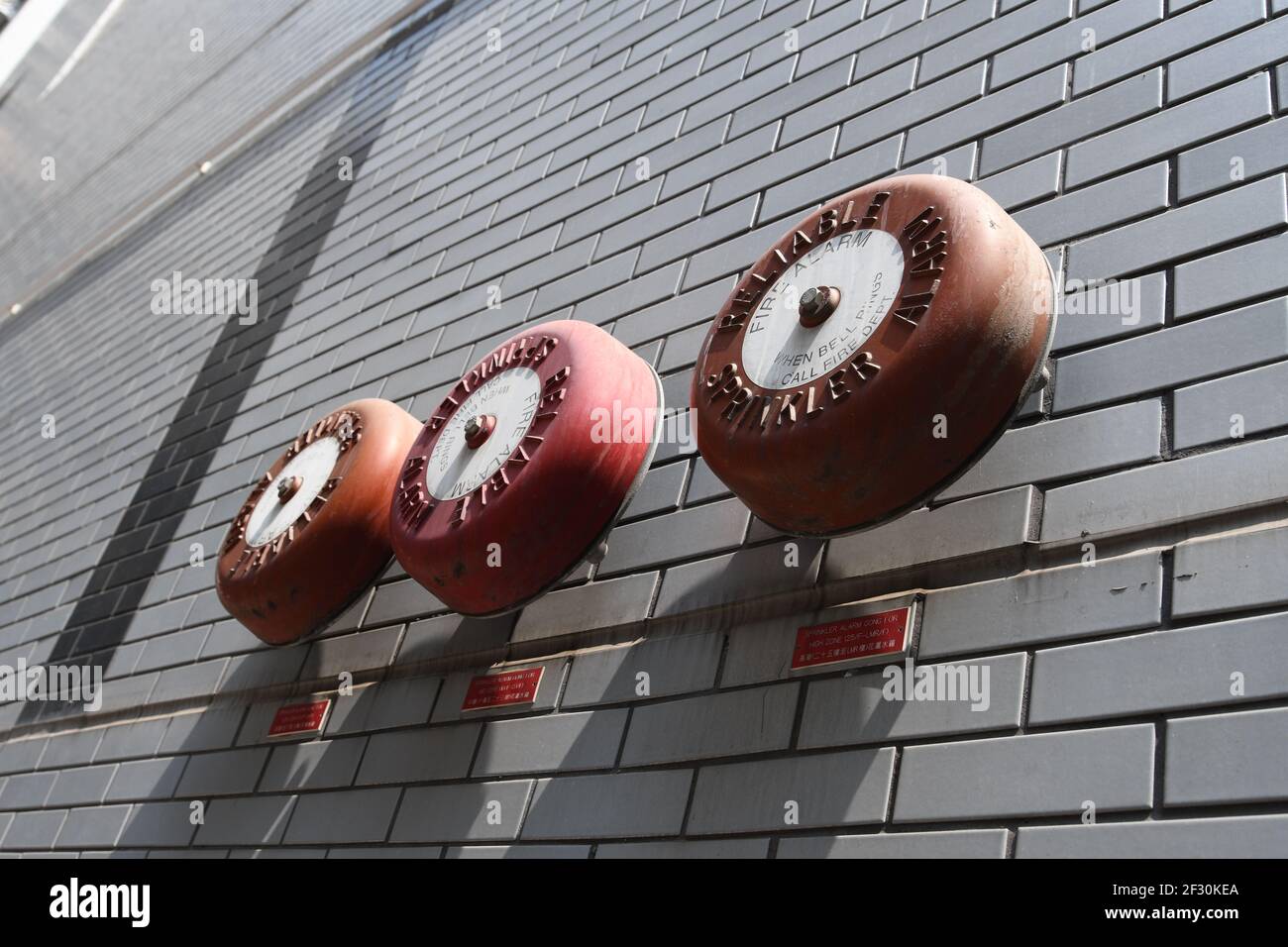 Closeup of three red fire sprinkler alarms mounted on a grey brick wall Stock Photo