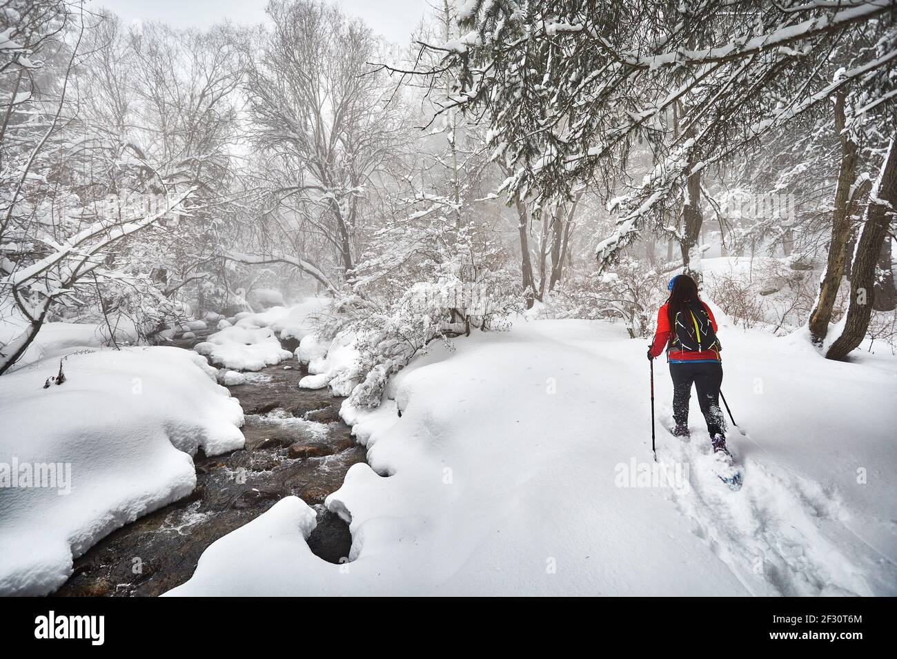 Woman wearing with show shoes is walking in the winter snowy forest near the river in Almaty, Kazakhstan Stock Photo