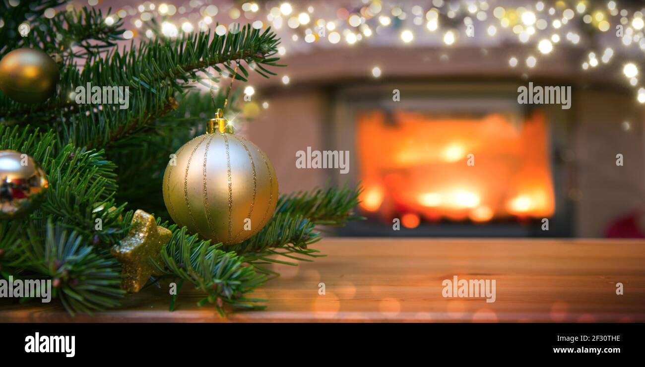 Christmas background with golden bauble , fireplace and fir tree branch ...