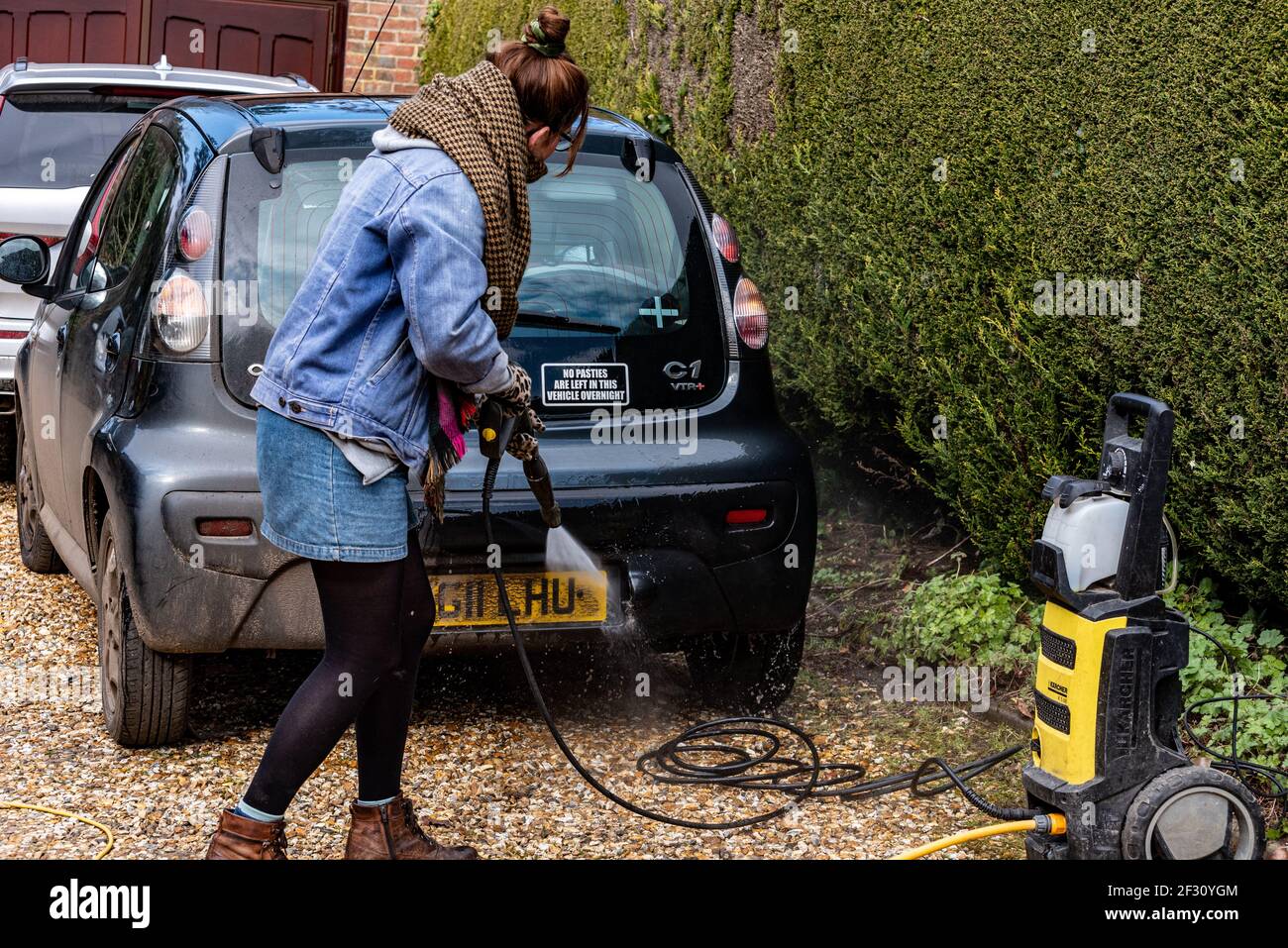 Woman cleaning a car with a pressure washer, Alresford, Hampshire, UK Stock Photo