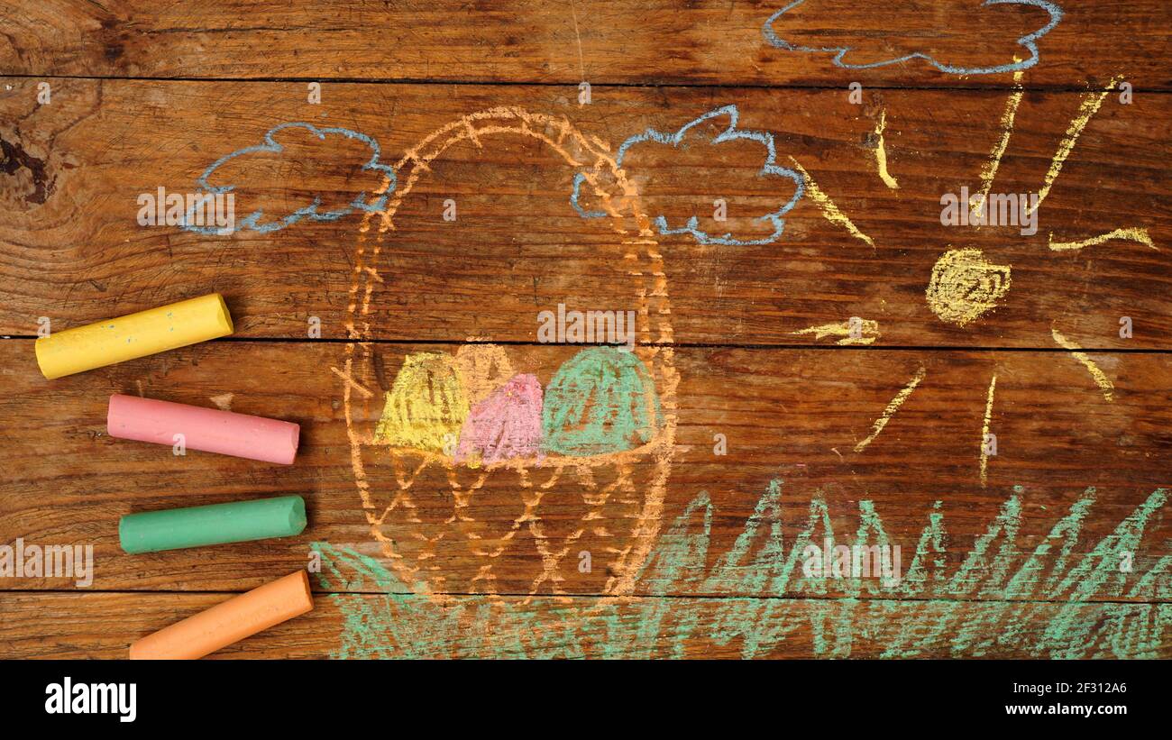Drawing with crayons on a wooden background. Easter eggs in a basket Stock Photo