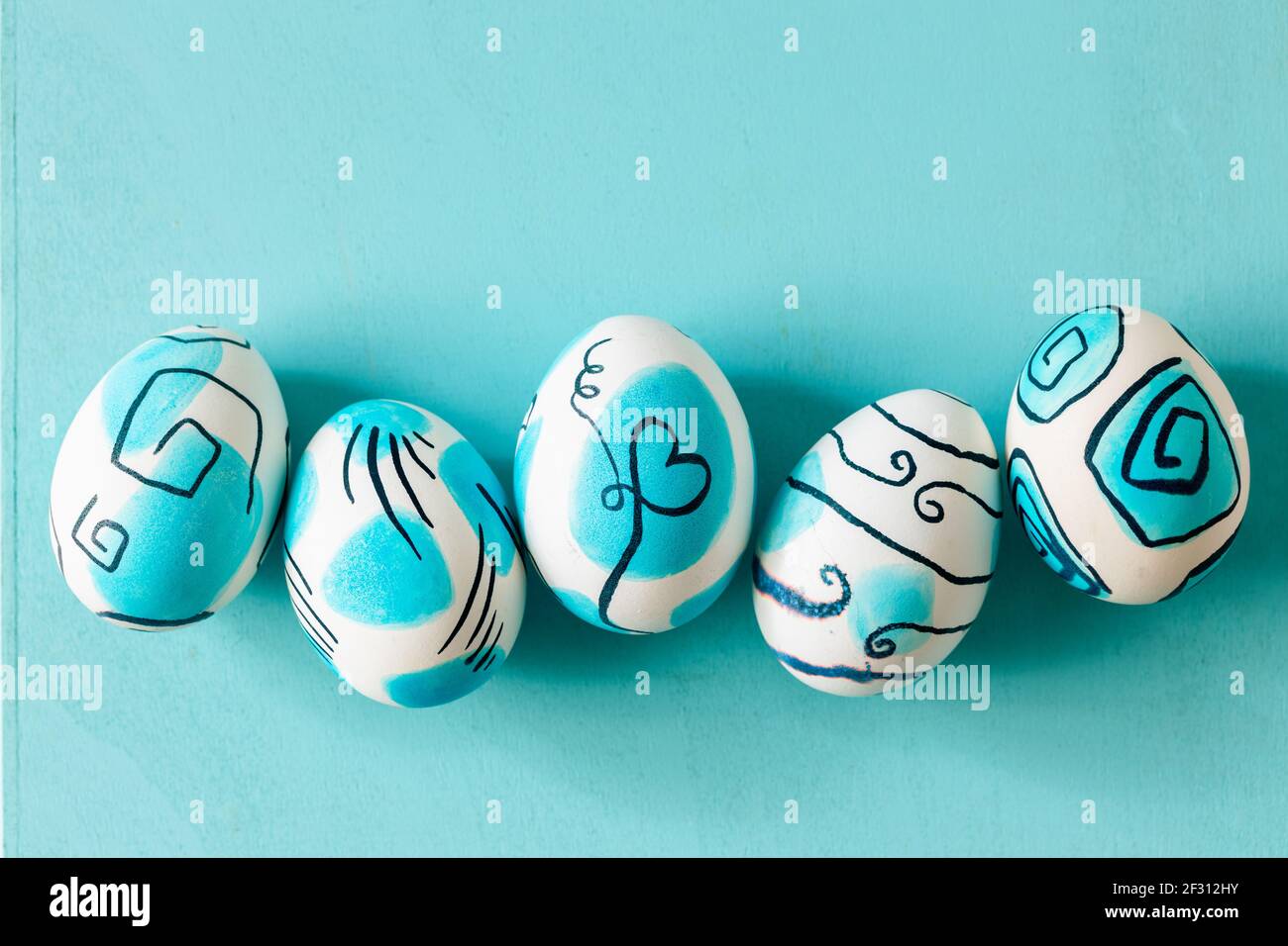Creative trendy painted easter eggs on turquoise background. Easter ideas. Stock Photo