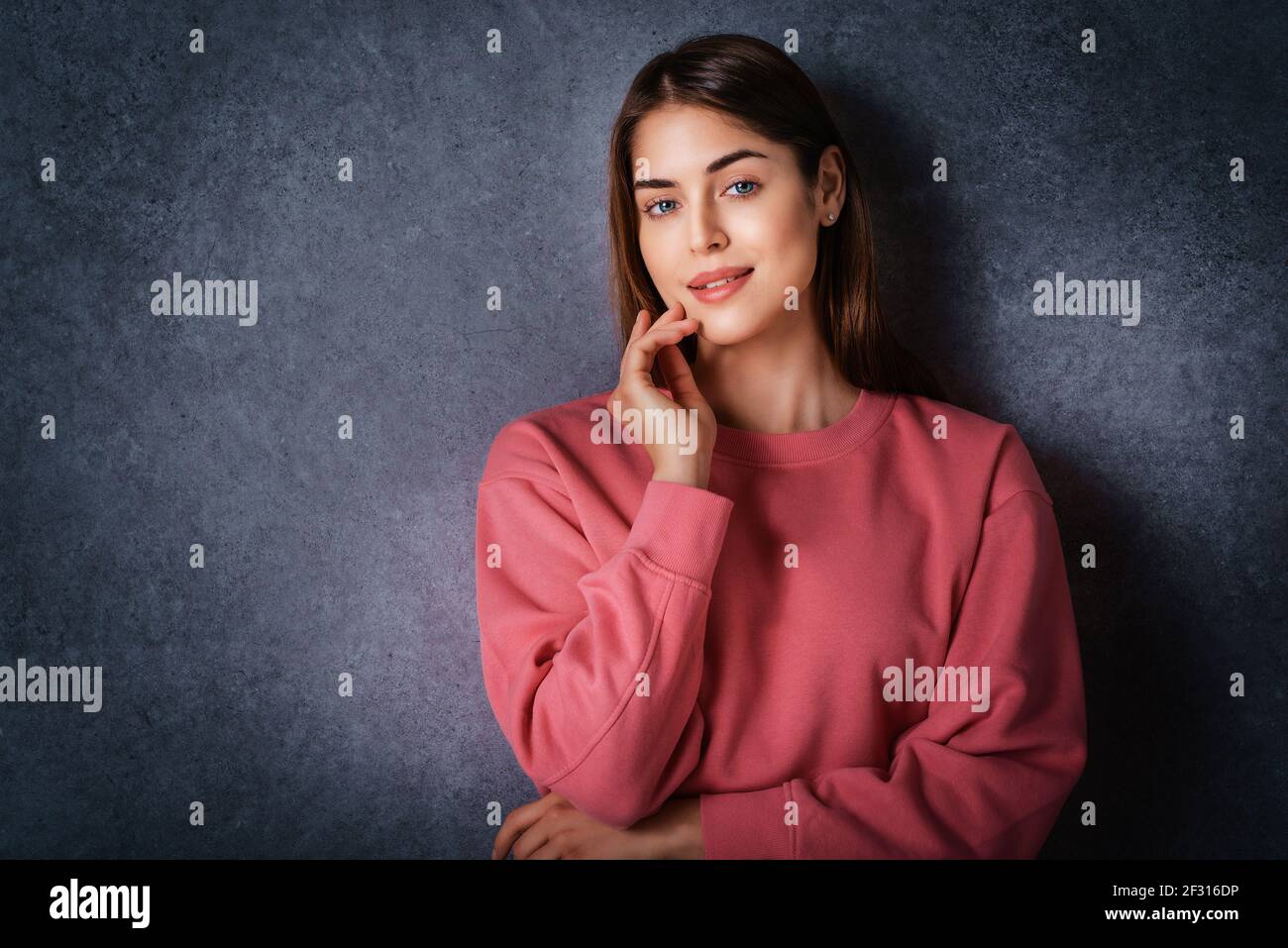 Studio portrait of beautiful young woman looking at camera and smiling ...