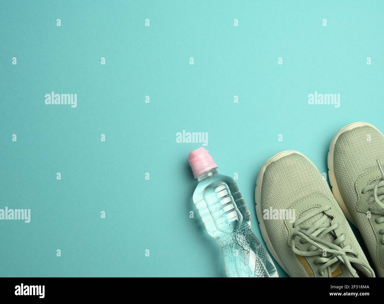 https://c8.alamy.com/comp/2F318MA/pair-of-sports-sneakers-and-a-bottle-with-mineral-water-on-a-blue-background-top-view-2F318MA.jpg