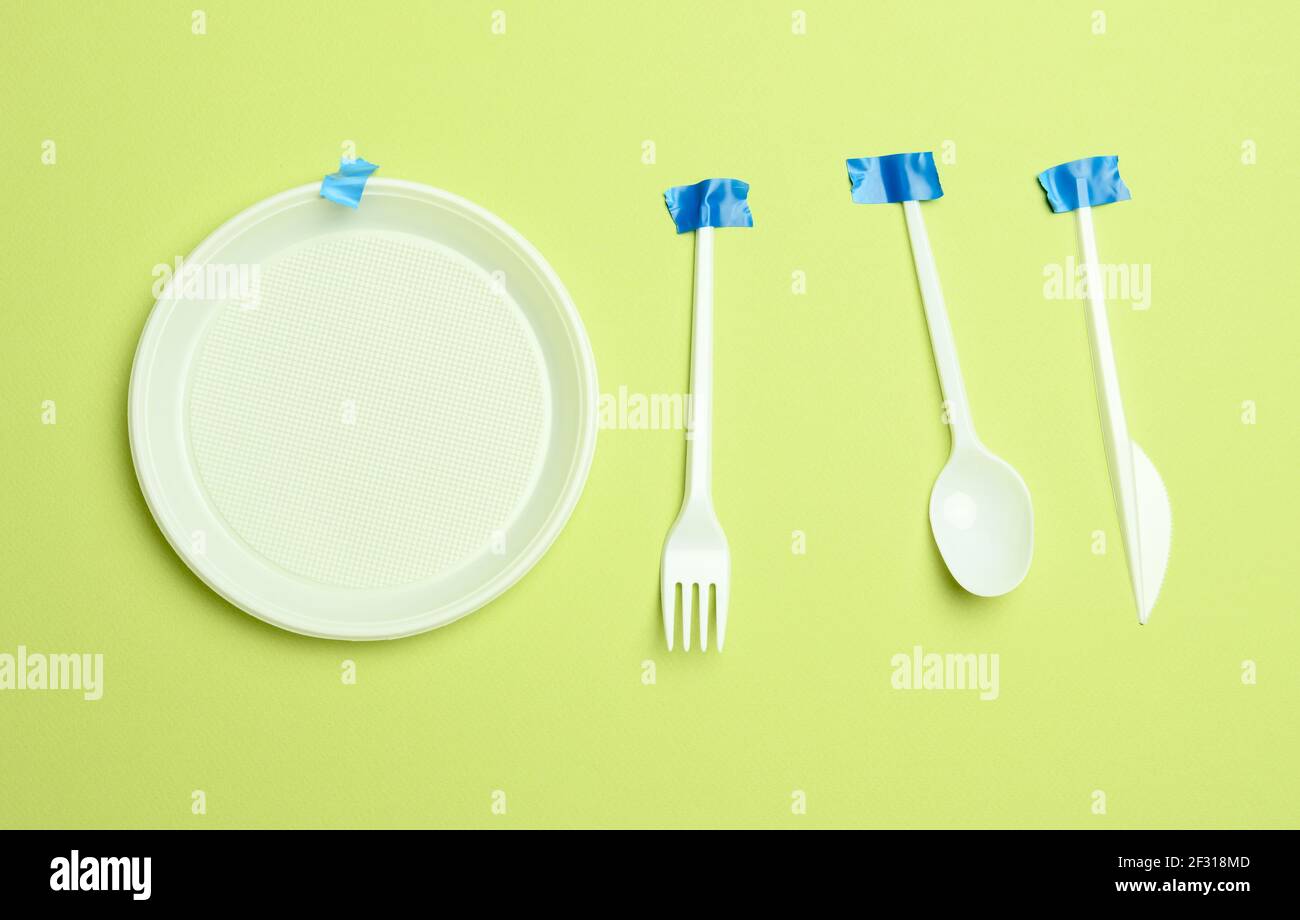Disposable plastic forks and spoons glued with blue tape on a green