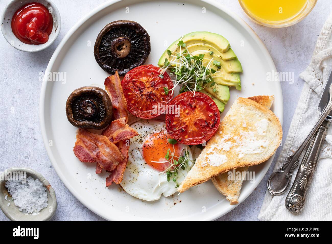 Breakfast with fried egg, tomatoes, mushroom, bacon and avocado Stock Photo