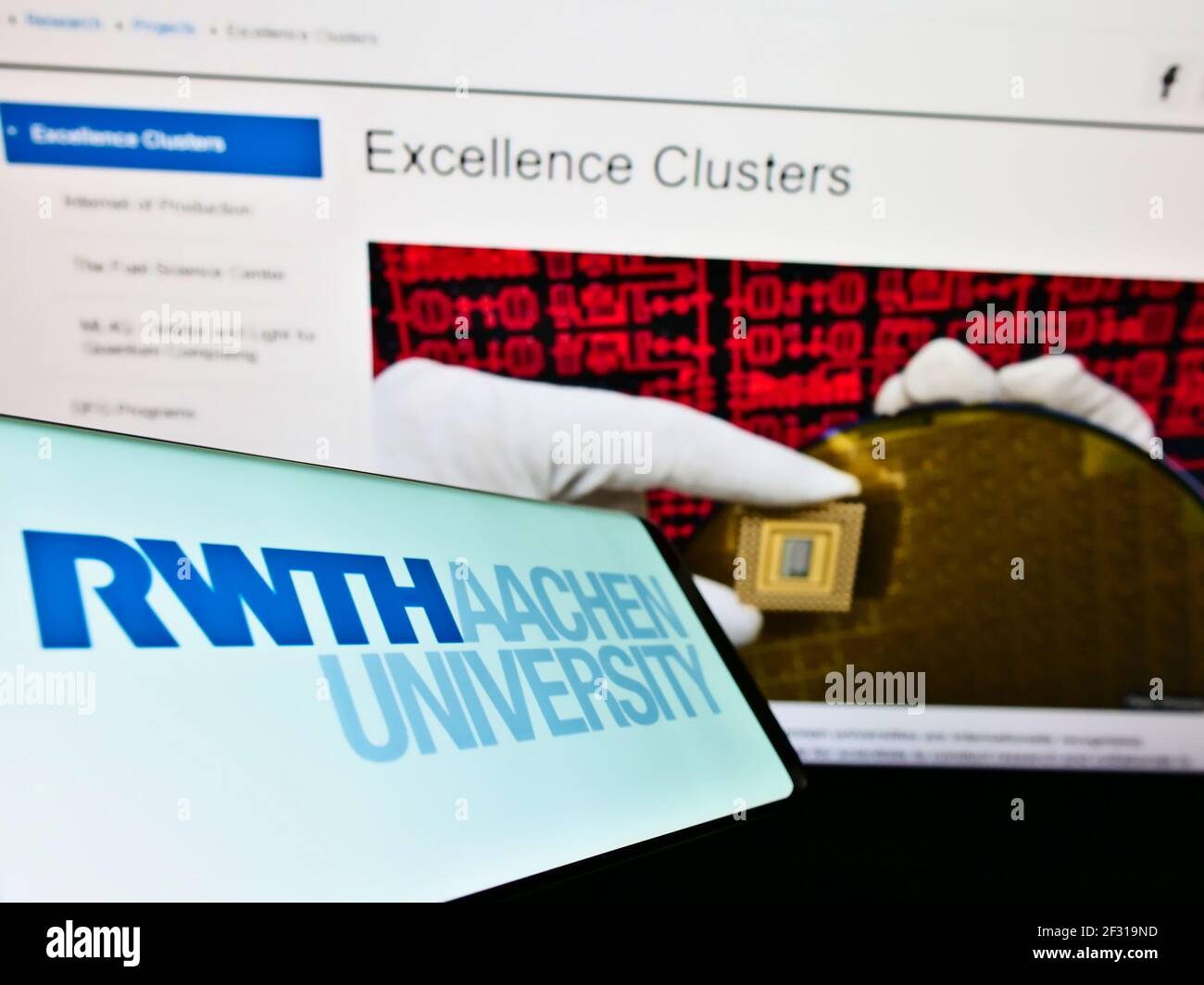 Mobile phone with logo of German education institution RWTH Aachen University on screen in front of website. Focus on center-right of phone display. Stock Photo