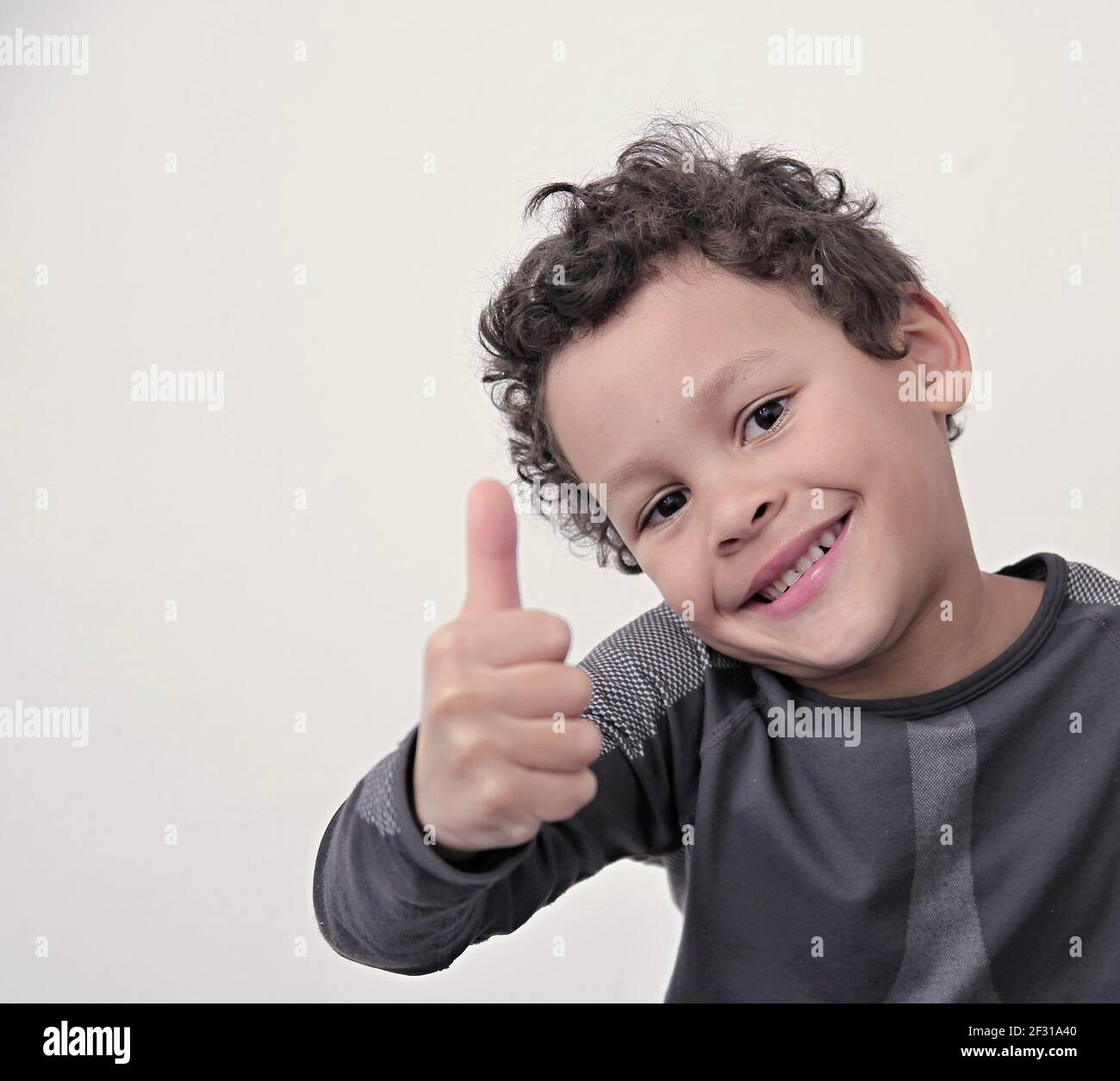 boy with thumbs up gesture on grey background with people stock photos Stock Photo