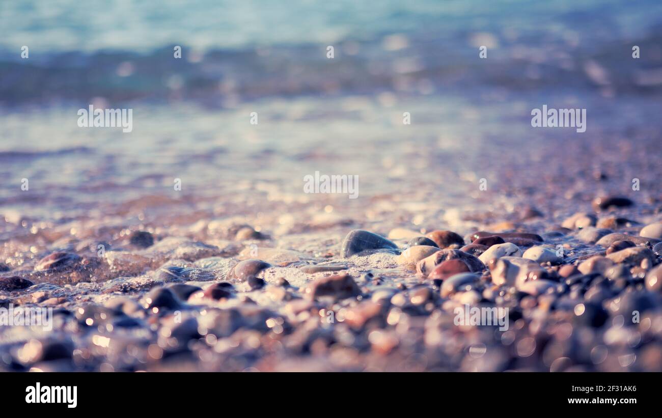 Waves washing over gravel beach, macro shot. Stock Photo