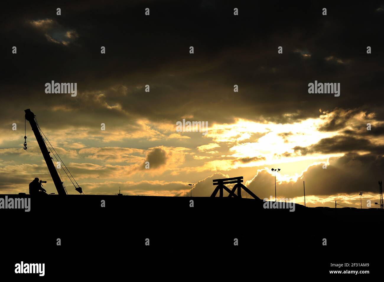 A photographer sitting on the end of the coal stage ramp at sunset. Stock Photo