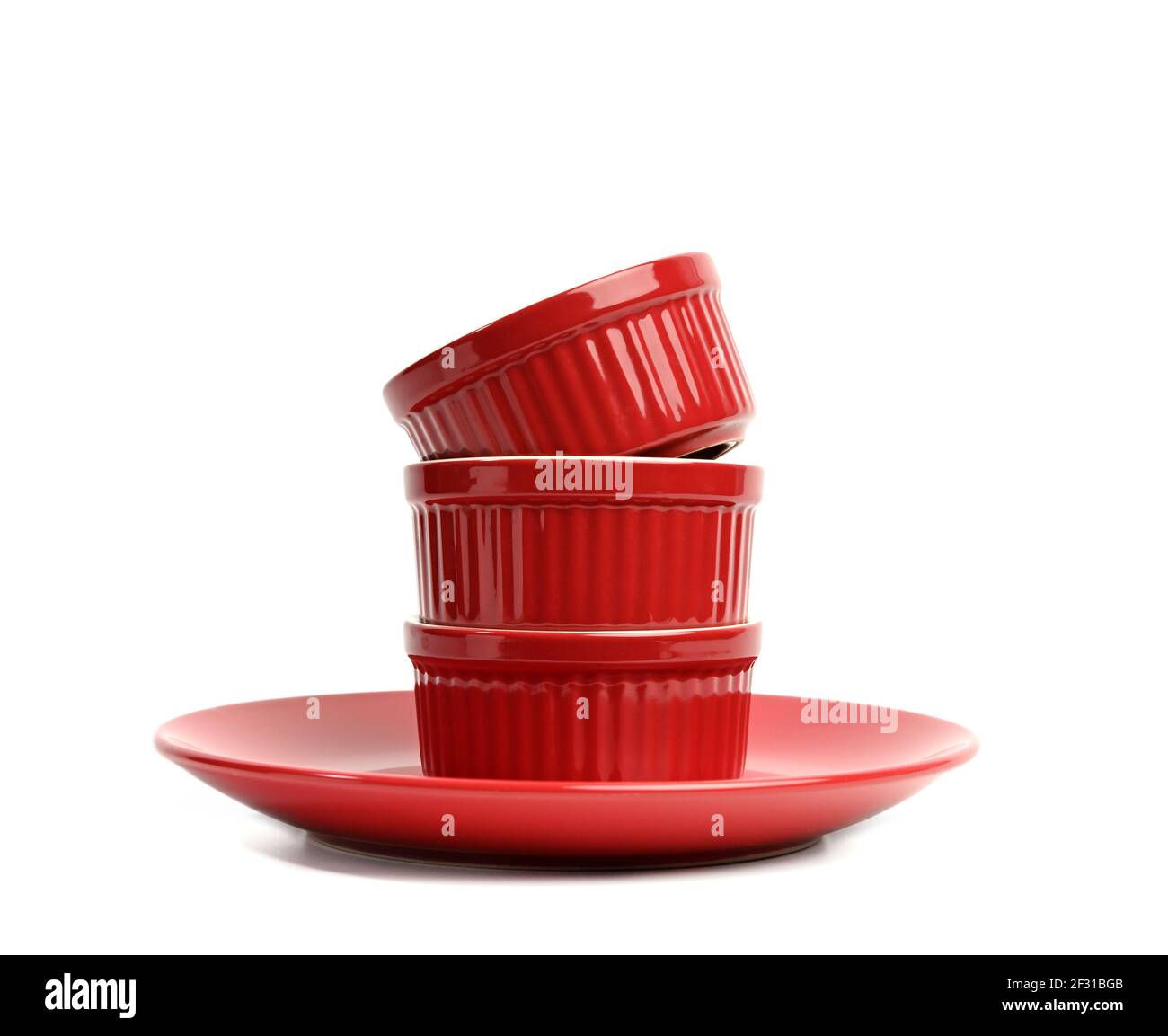 Stack of red ceramic round cupcake baking dishes isolated on white background Stock Photo