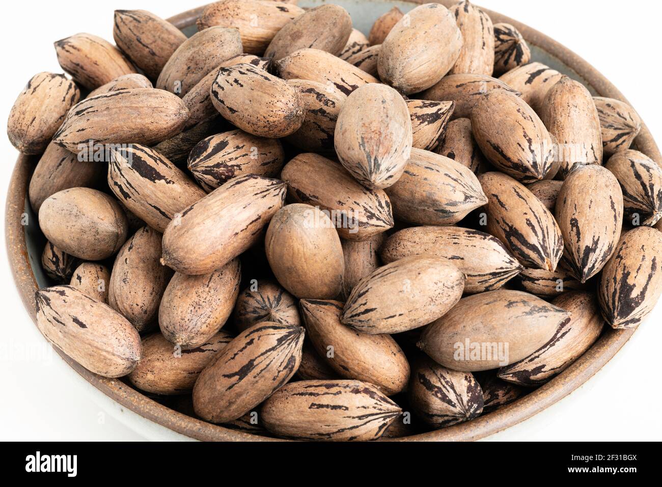 In-shell pecan nuts on bowl set on plain white background. Stock Photo