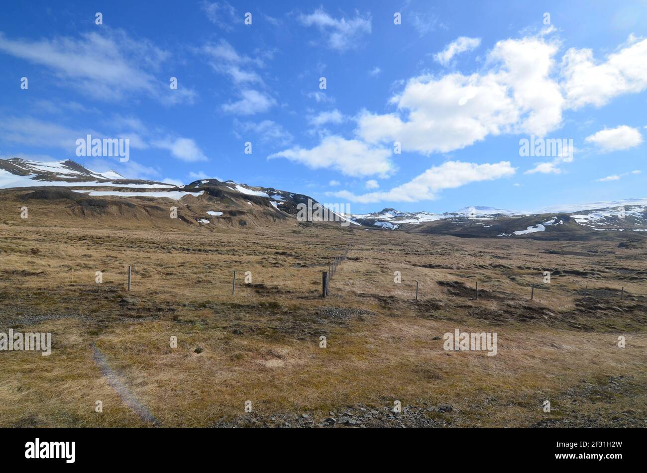 Farmland at the base of a snow covered mountains in Iceland Stock Photo