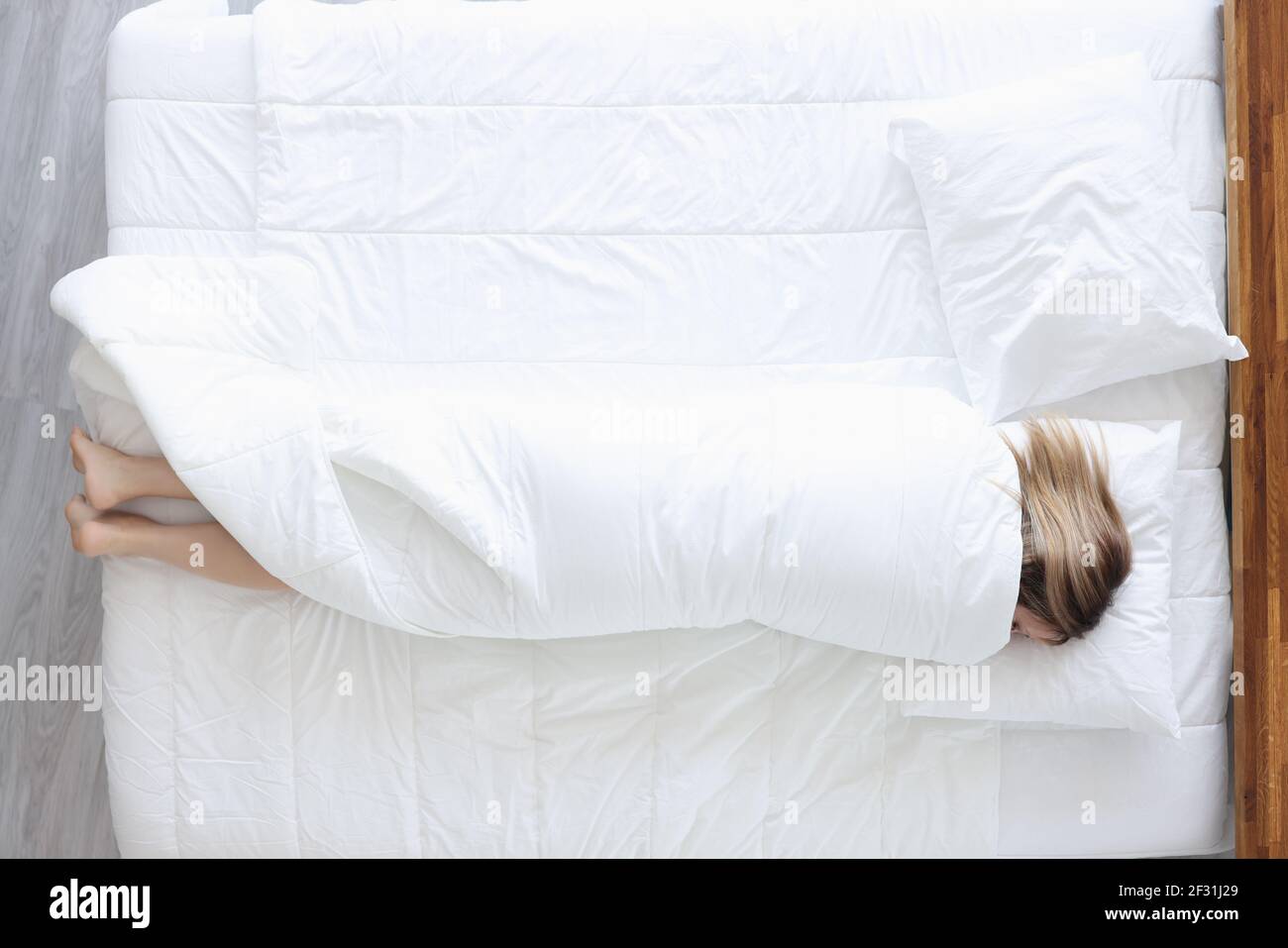 Sleeping woman lies on bed wrapped in blanket Stock Photo Alamy