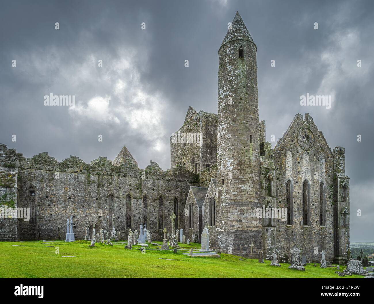 Graveyard with Celtic crosses and tombstones in front of majestic Rock of Cashel castle, County Tipperary, Ireland Stock Photo