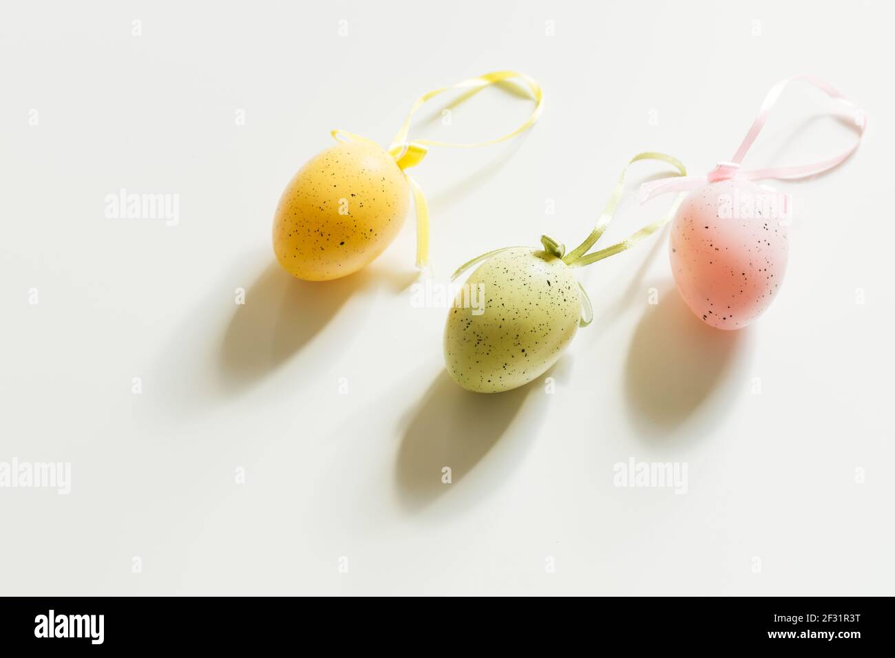 Three colored easter eggs on a white table, bright sunlight. Hope Stock Photo