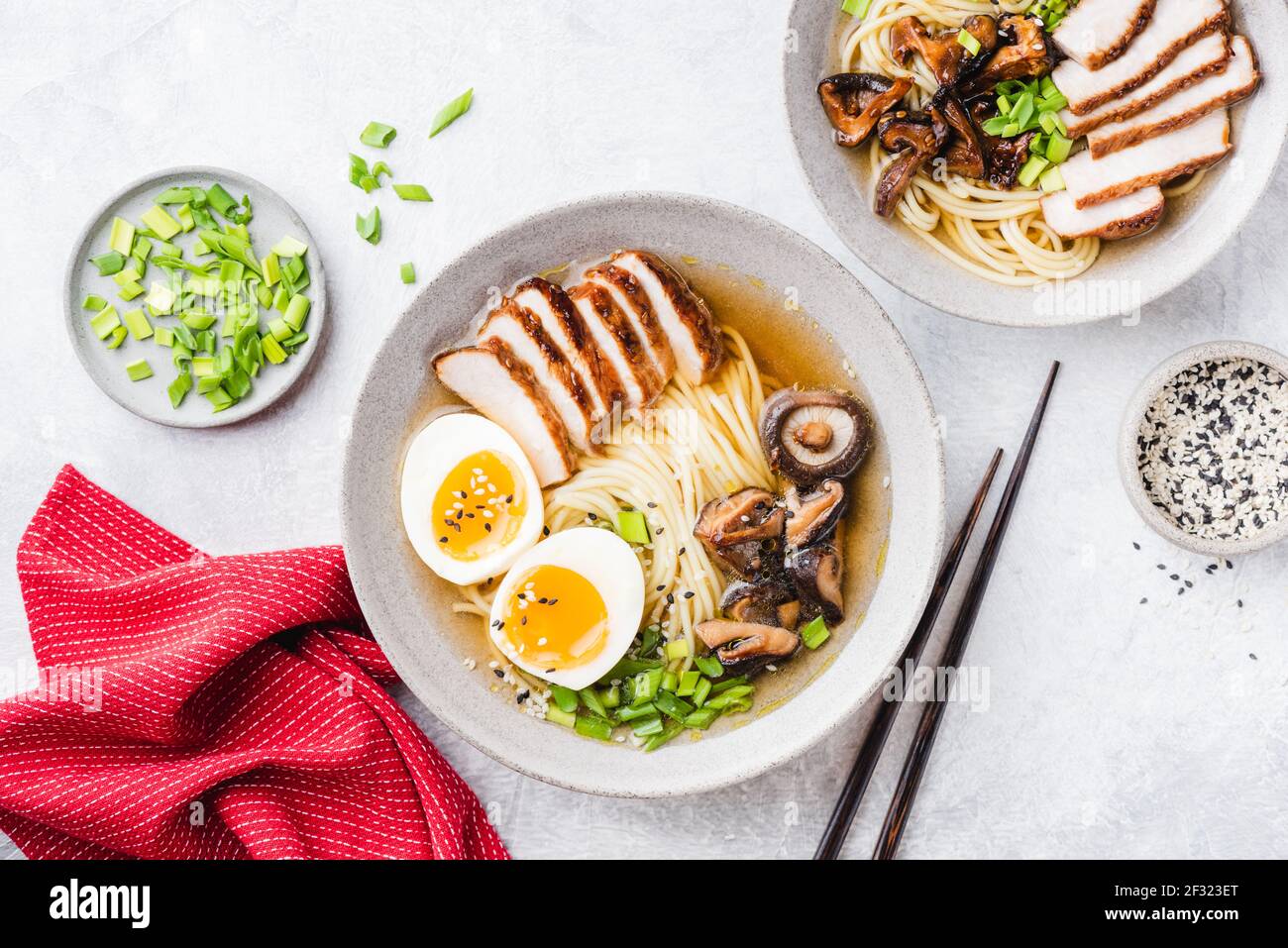 Chicken shiitake ramen noodle soup bowl on a grey concrete background, top view. Asian cuisine food, noodle soup with chicken, shiitake, egg and green Stock Photo