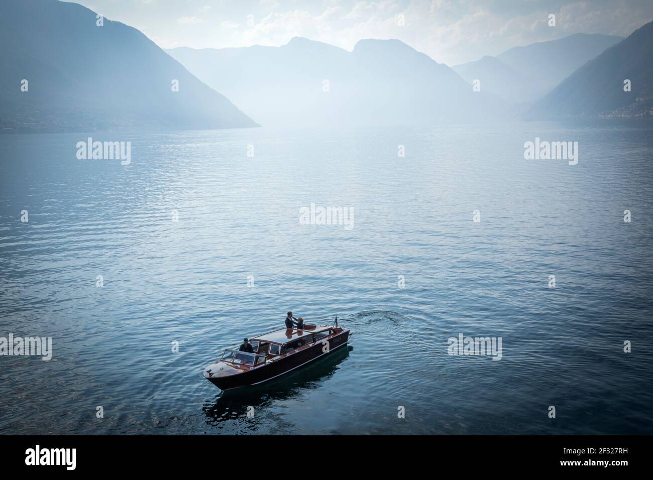 Italy, Lombardy, Lenno, view of Lake Como from Villa del Balbianello, couple embracing on a wooden speedboat Stock Photo