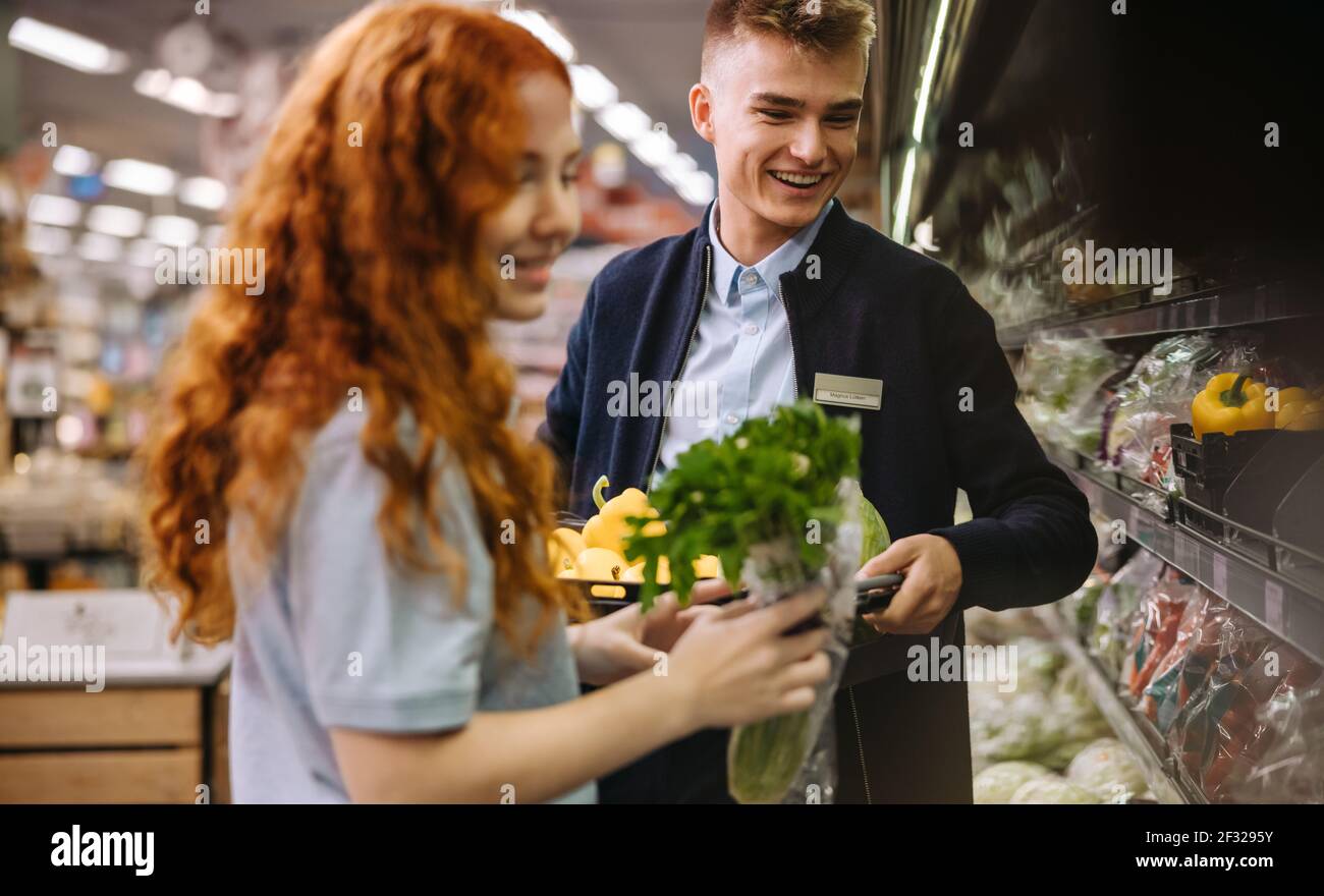 Supermarket assistants packing fresh produce on the shelves. Grocery