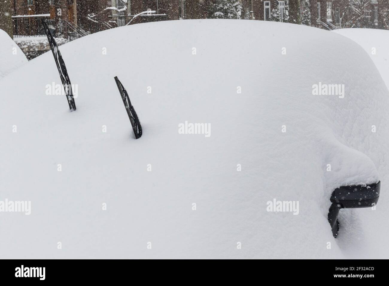 Snow buried car with windshield wipers standing up after snowstorm hi