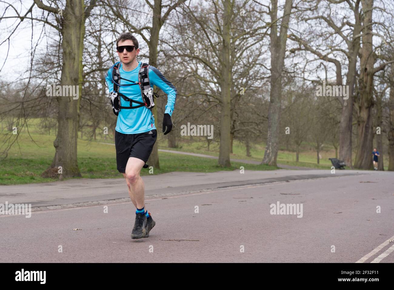 a male runner in sun glasses with rucksack and black shorts runs in