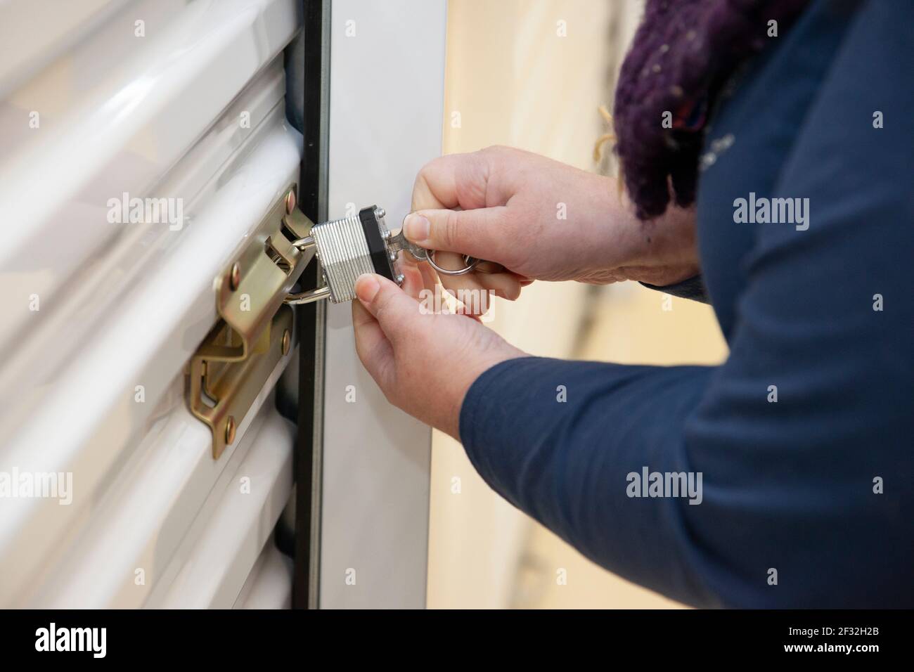 A person uses a key to gain access or unlock their padlocked secure unit Stock Photo