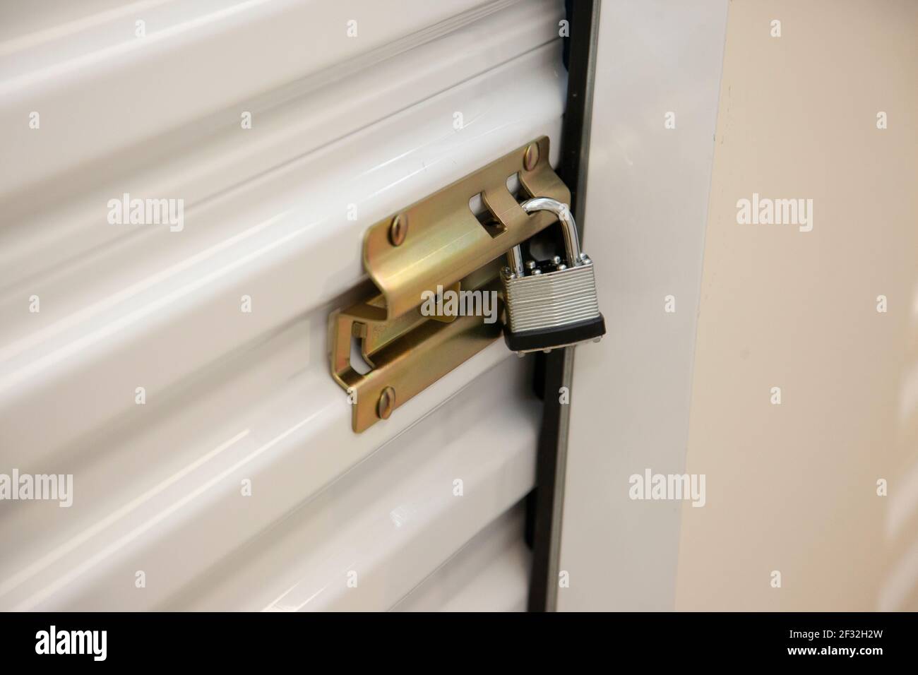 Metal door to an individual storage compartment held shut and locked with a metal padlock Stock Photo