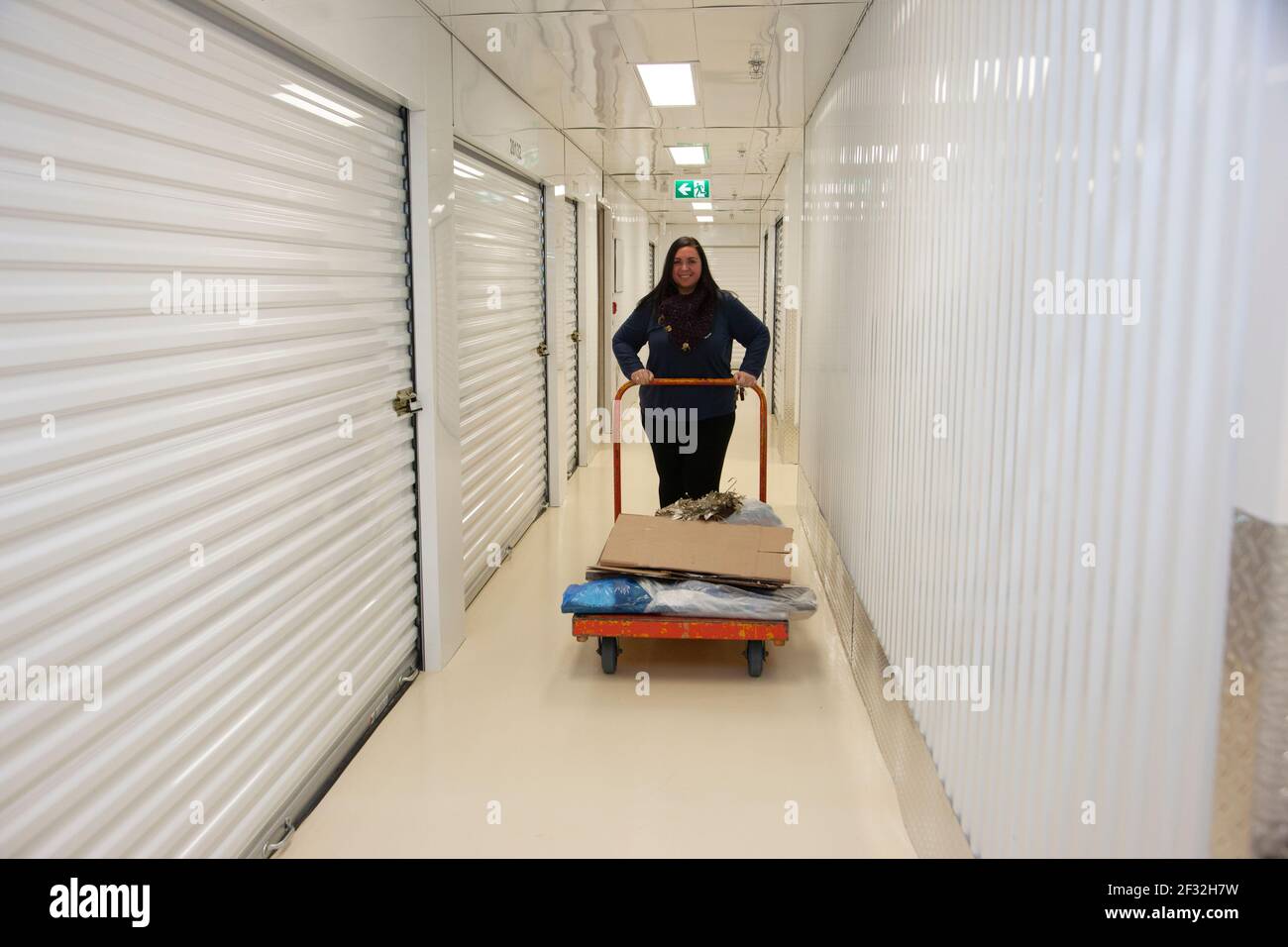 Woman smiling as she moves some items and boxes into her metal storage container Stock Photo