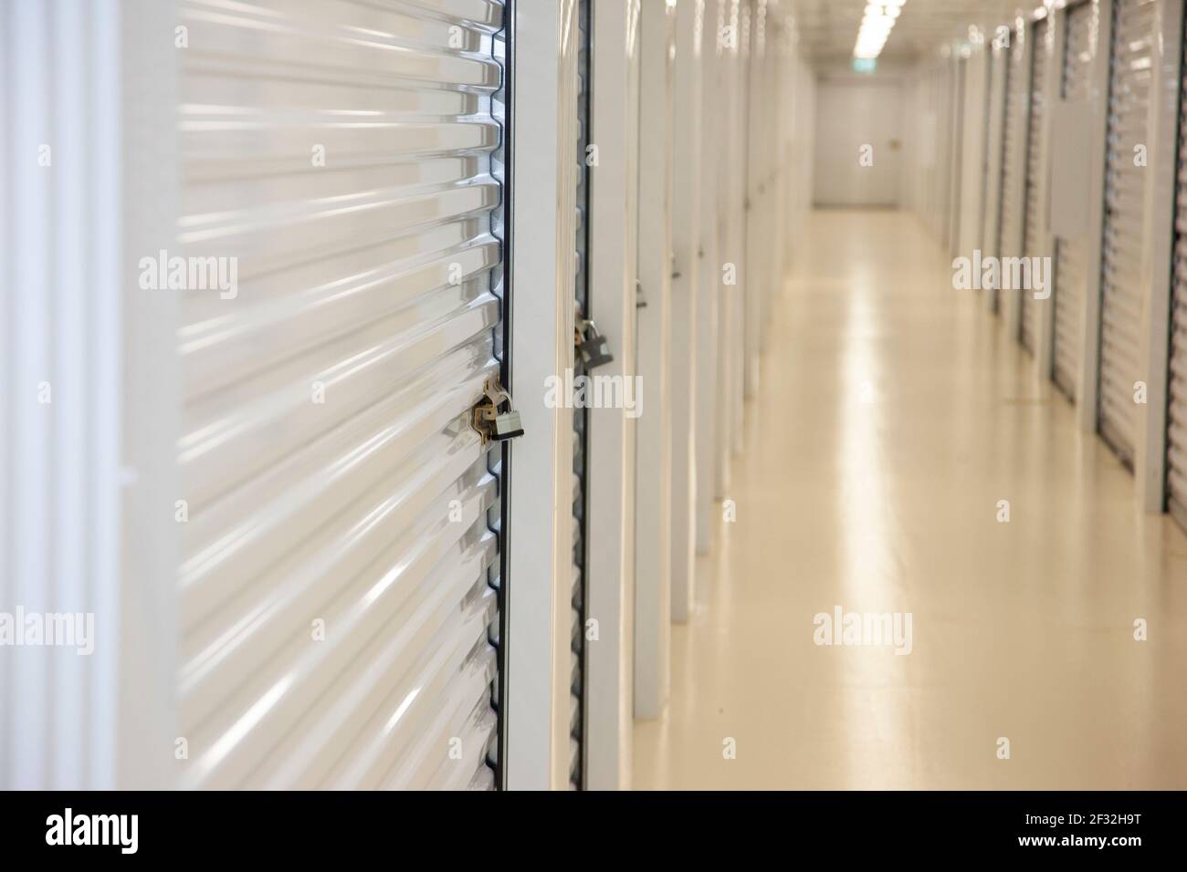 Close view of an empty storage hallway with a secured padlock Stock Photo
