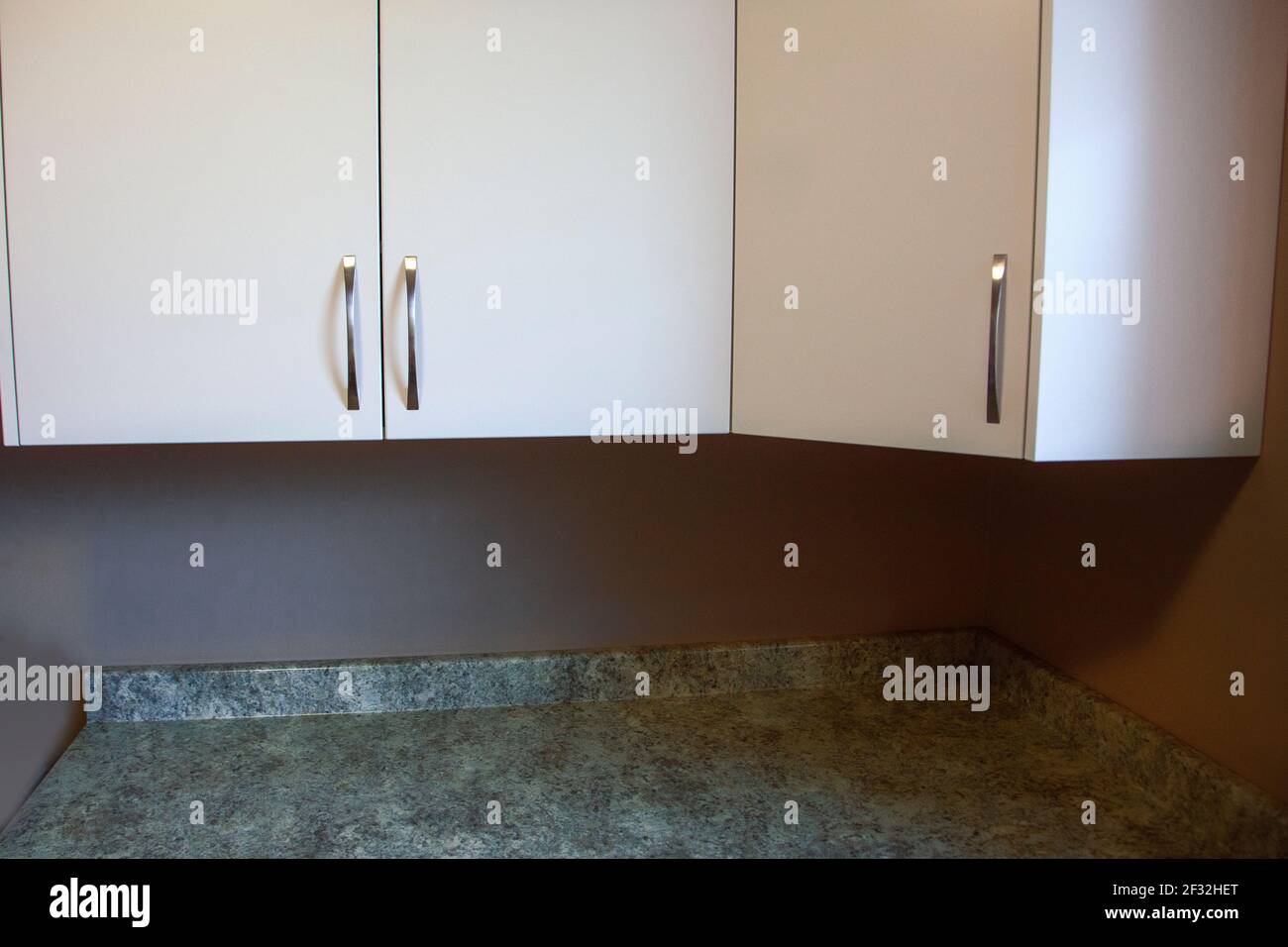 granite countertops and a white set of cupboards with silver handles Stock Photo