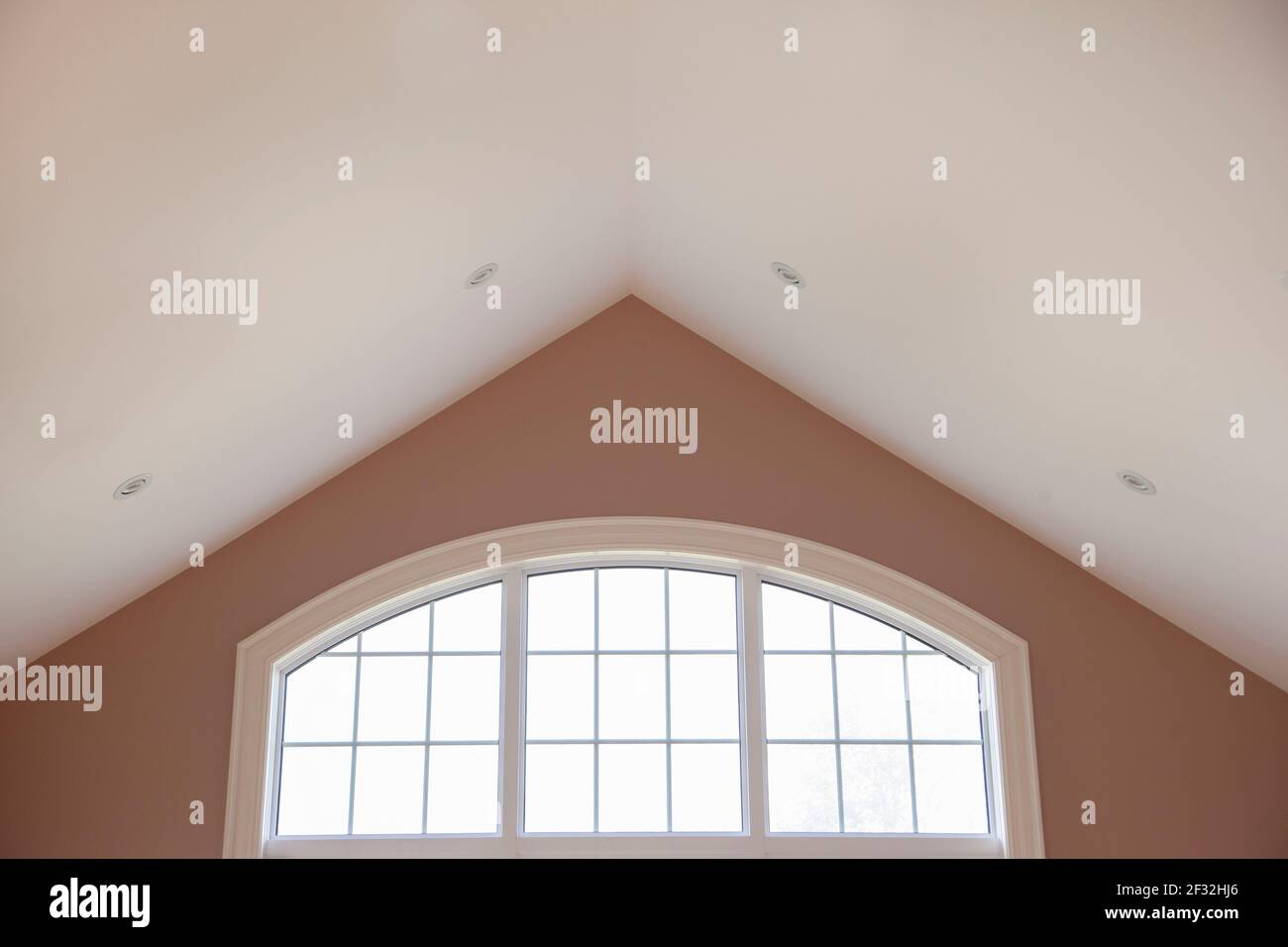 a glass window with white frame set against a big vaulted ceiling in a beautiful home Stock Photo