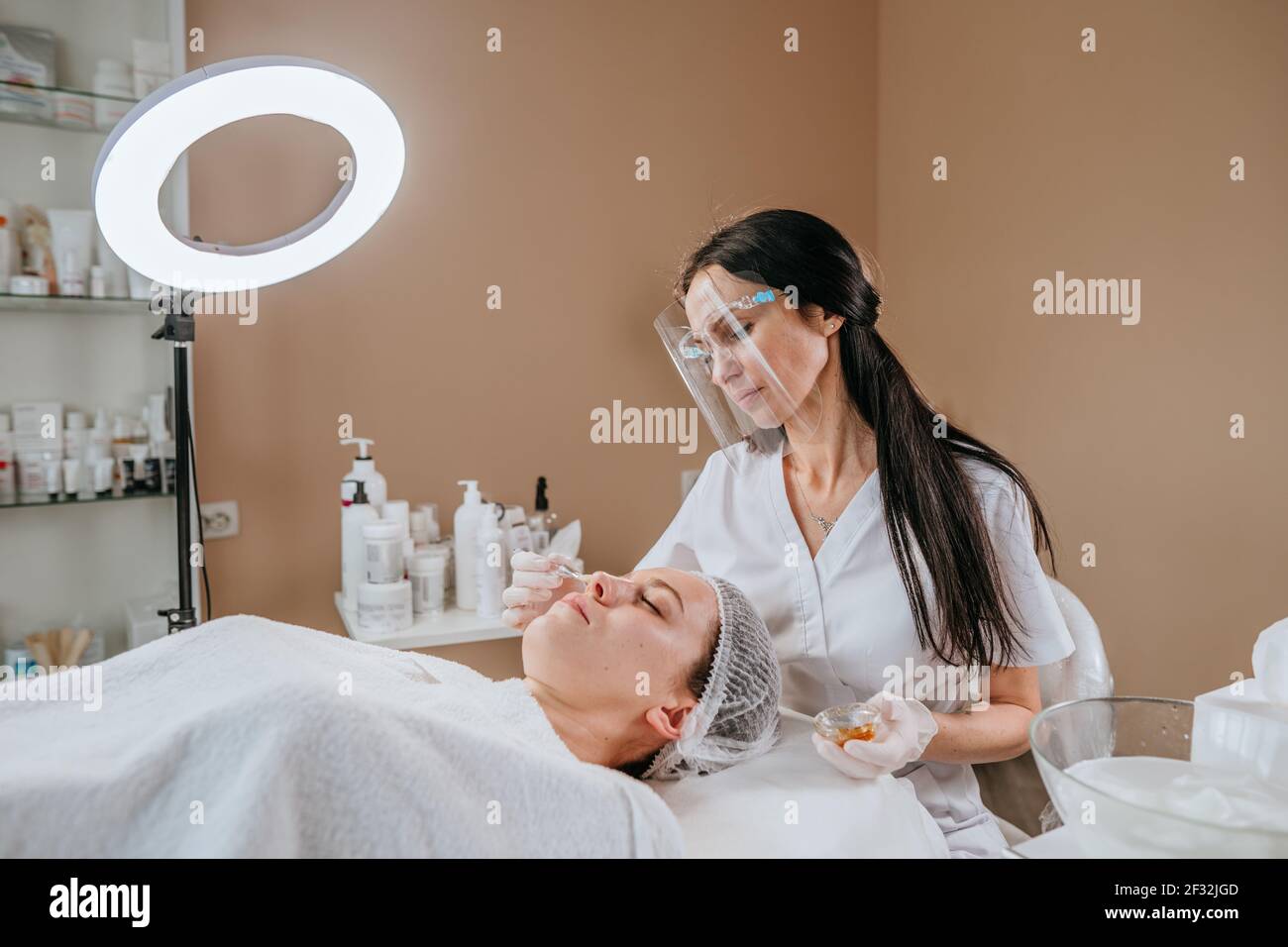 Esthetician or facialist making facial cleansing procedure to a woman in a beauty salon Stock