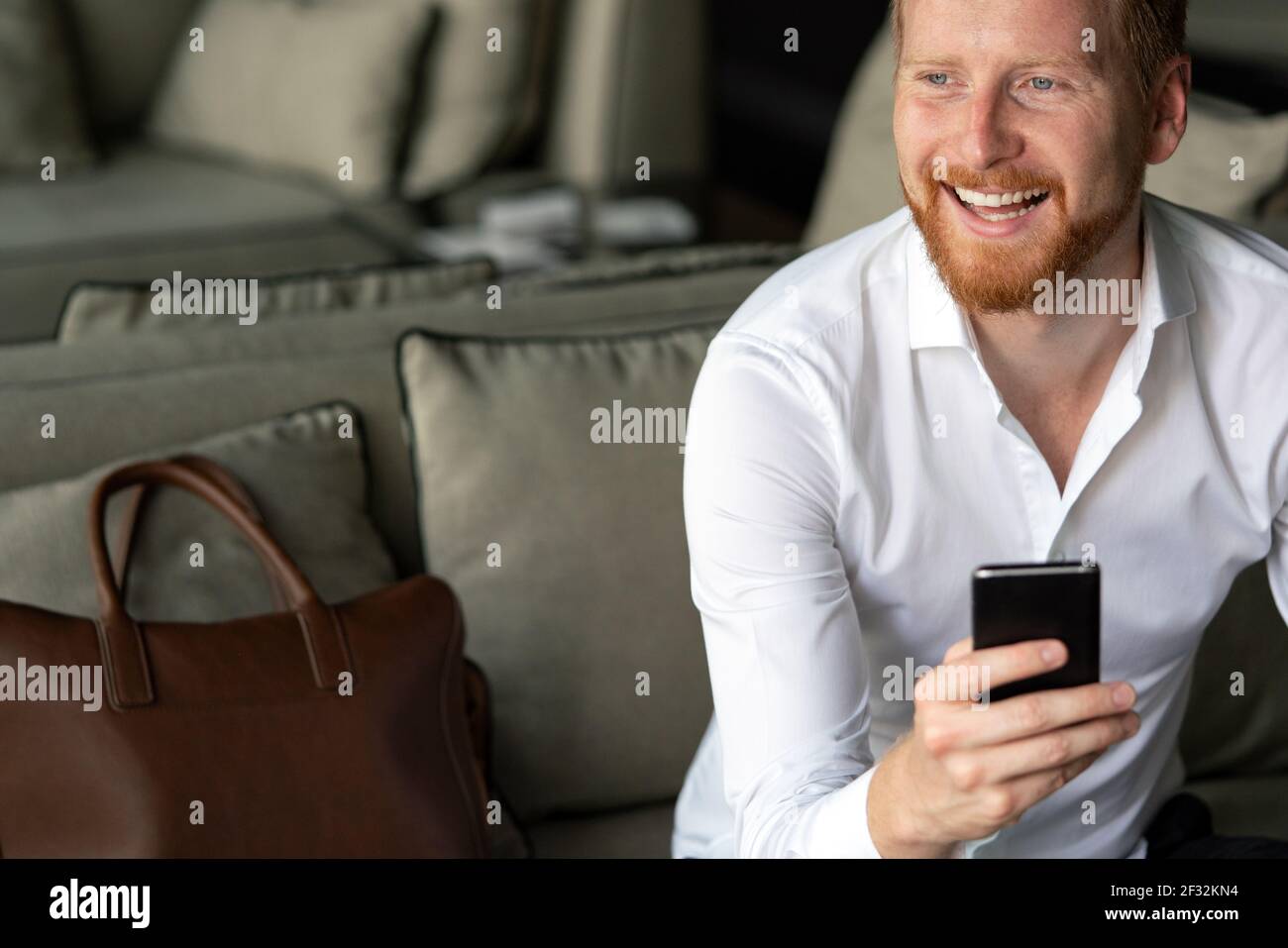 Happy young man using his smart phone at office Stock Photo