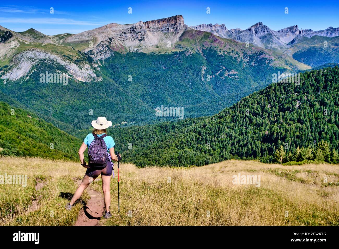 Hiker woman in a mountains and grasslands landscape. Castillo de Acher mountain route. Valles Occidentales Natural Park. Hecho valley. Pyrenees mounta Stock Photo