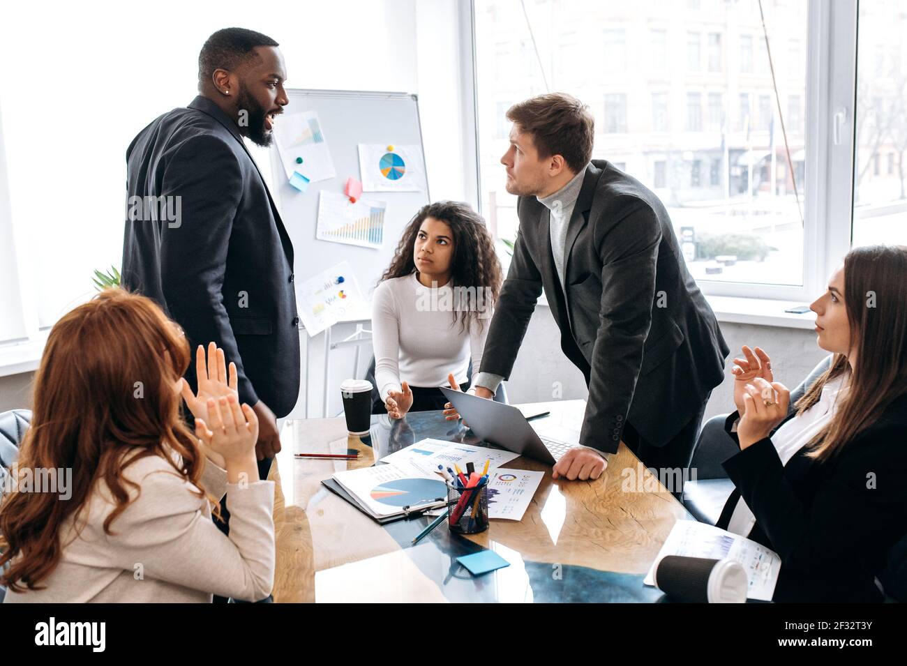 Frustrated tired colleagues are having a tense brainstorm at briefing meeting, can't make an agreement. Multiracial male and female employees arguing, have a work troubles, failed project Stock Photo
