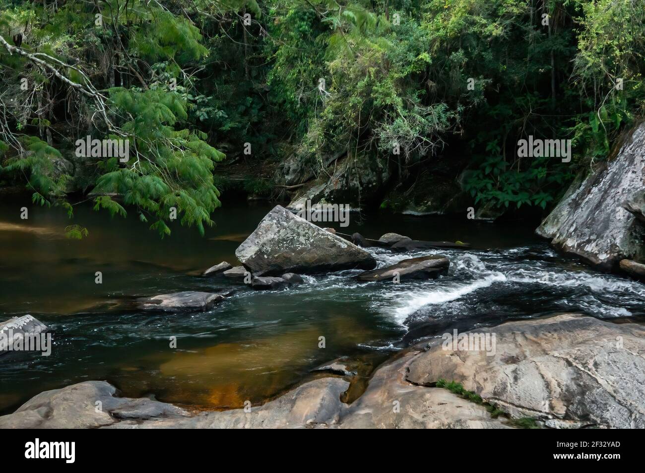 The water stream of Pimenta waterfall flowing between rocks into a natural pool in the middle Sea Ridge (Serra do Mar) forest. Stock Photo