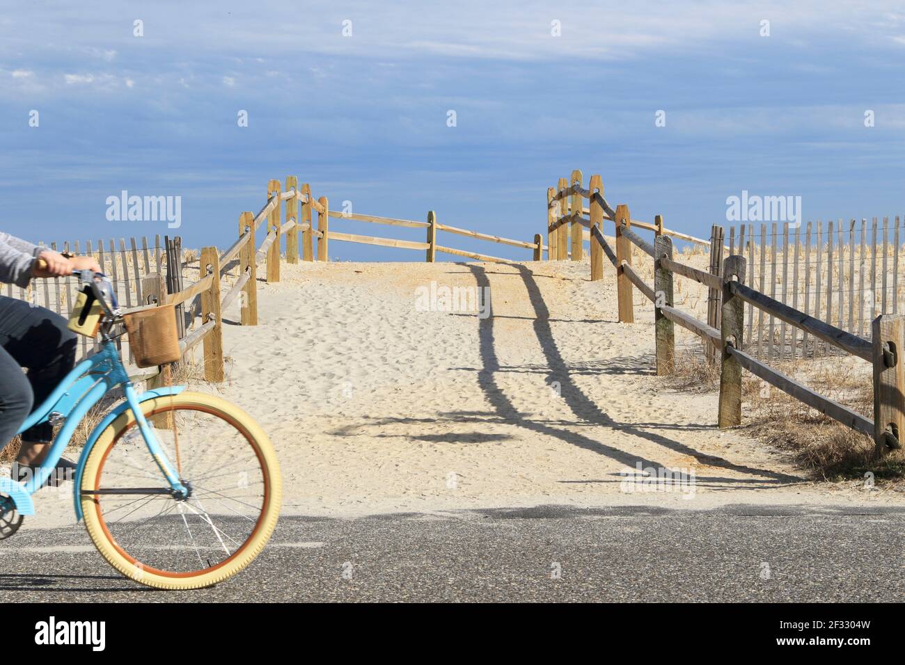Smile, You're in Sea Isle is the catch phrase of Sea Isle City, a shore town in New Jersey USA . A bicyclist passes a beach access ramp. Stock Photo
