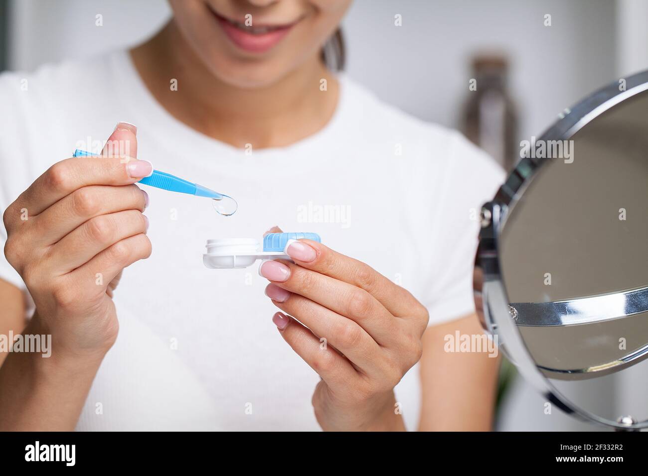 Young woman putting eye contact lens on her eyes Stock Photo