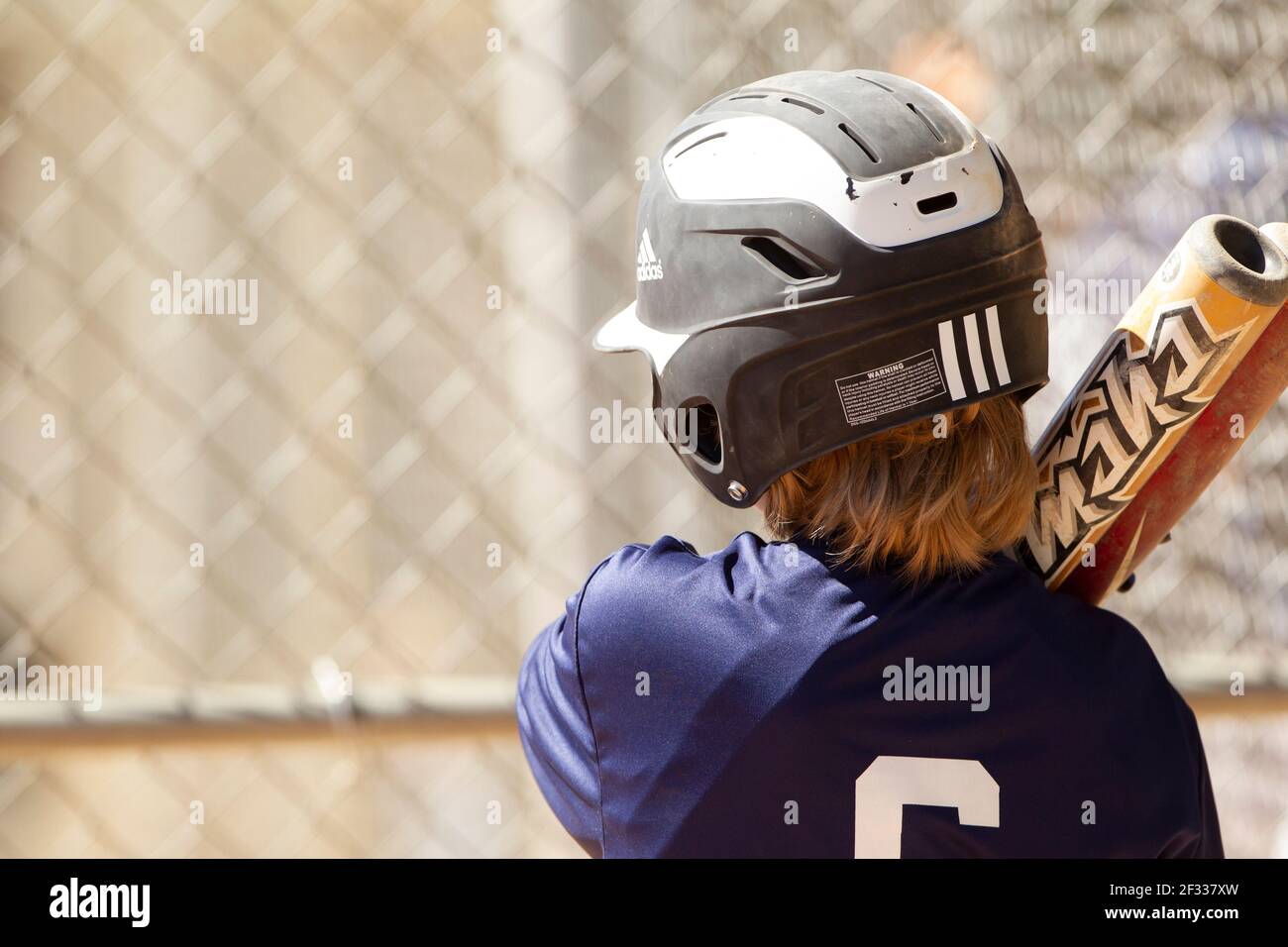A teenage baseball player prepares to bat during a youth league baseball game. Stock Photo