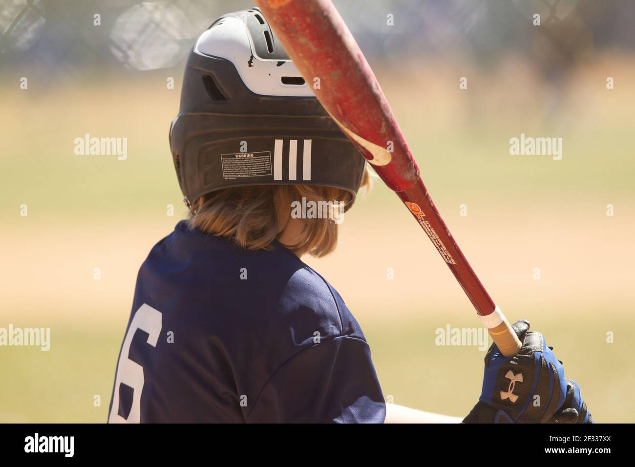 A teenage baseball player prepares to bat during a youth league baseball game. Stock Photo