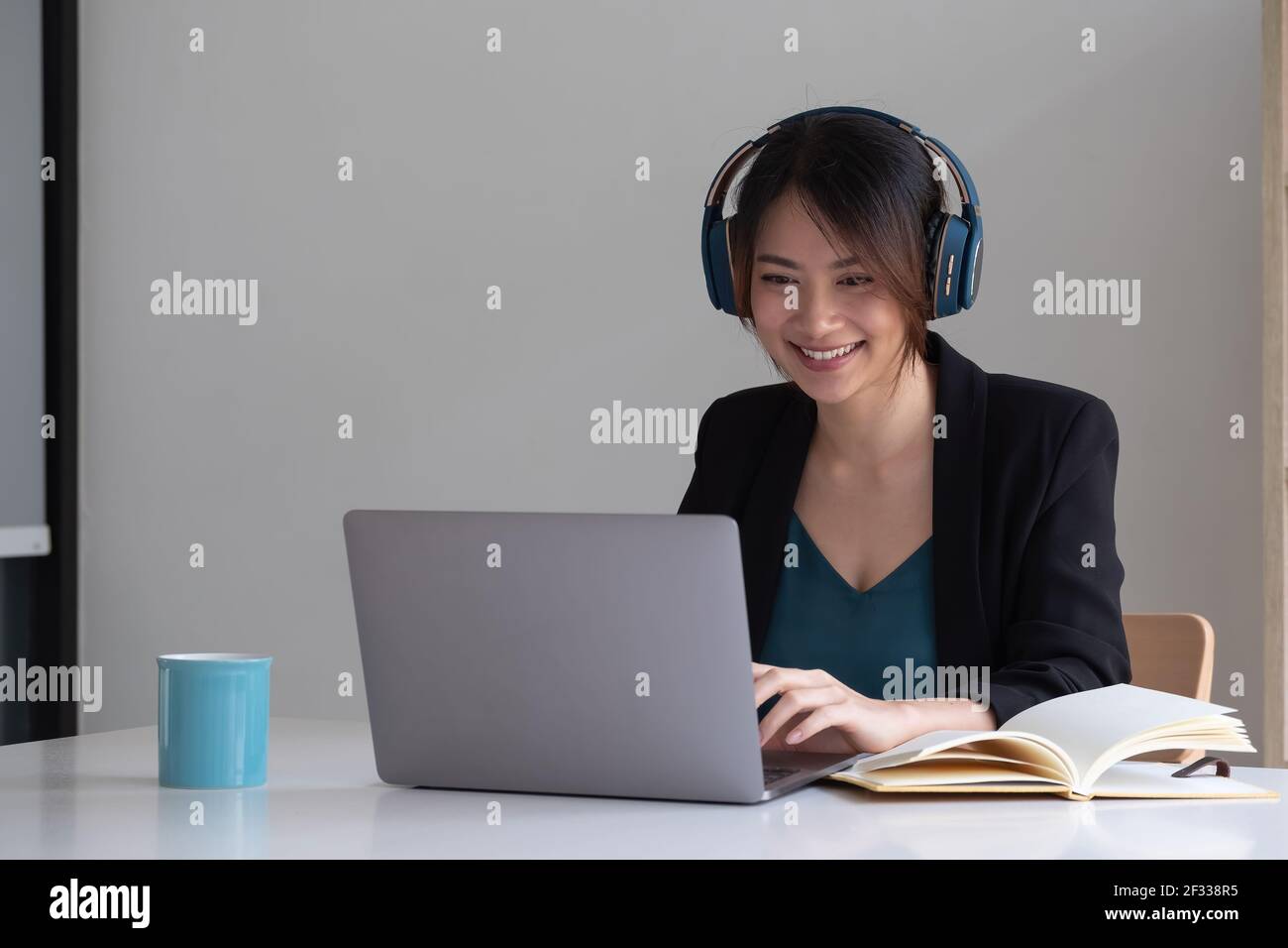 Happy asian woman wear headset laugh using laptop video stream conference call teach online, happy ethnic girl student gamer tutor have fun watch Stock Photo