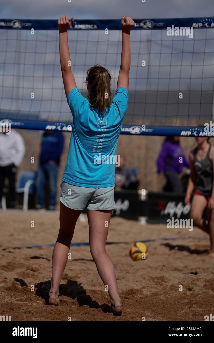A tall blonde teenage girl competes in the sport of beach volleyball. Stock Photo