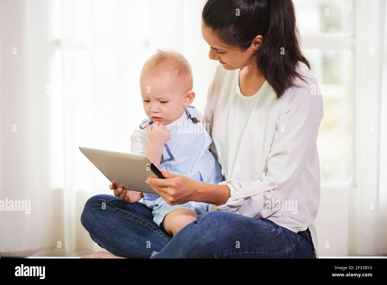 Young mother showing tablet computer with animated video on screen to