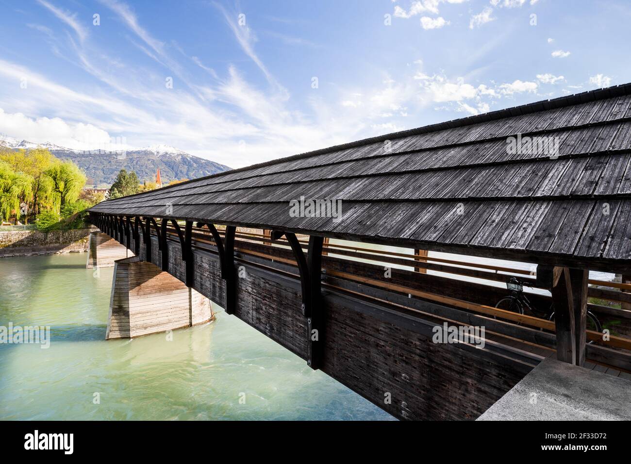 Wide angle view of a pedestrian covered bridge in Inssbruck, under a blue sky with streaked clouds Stock Photo