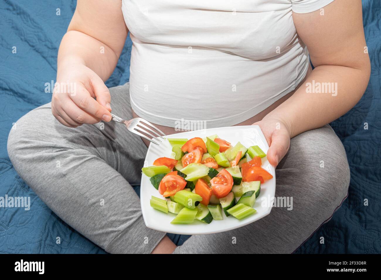 A pregnant woman is eating a healthy homemade organic fruit salad while